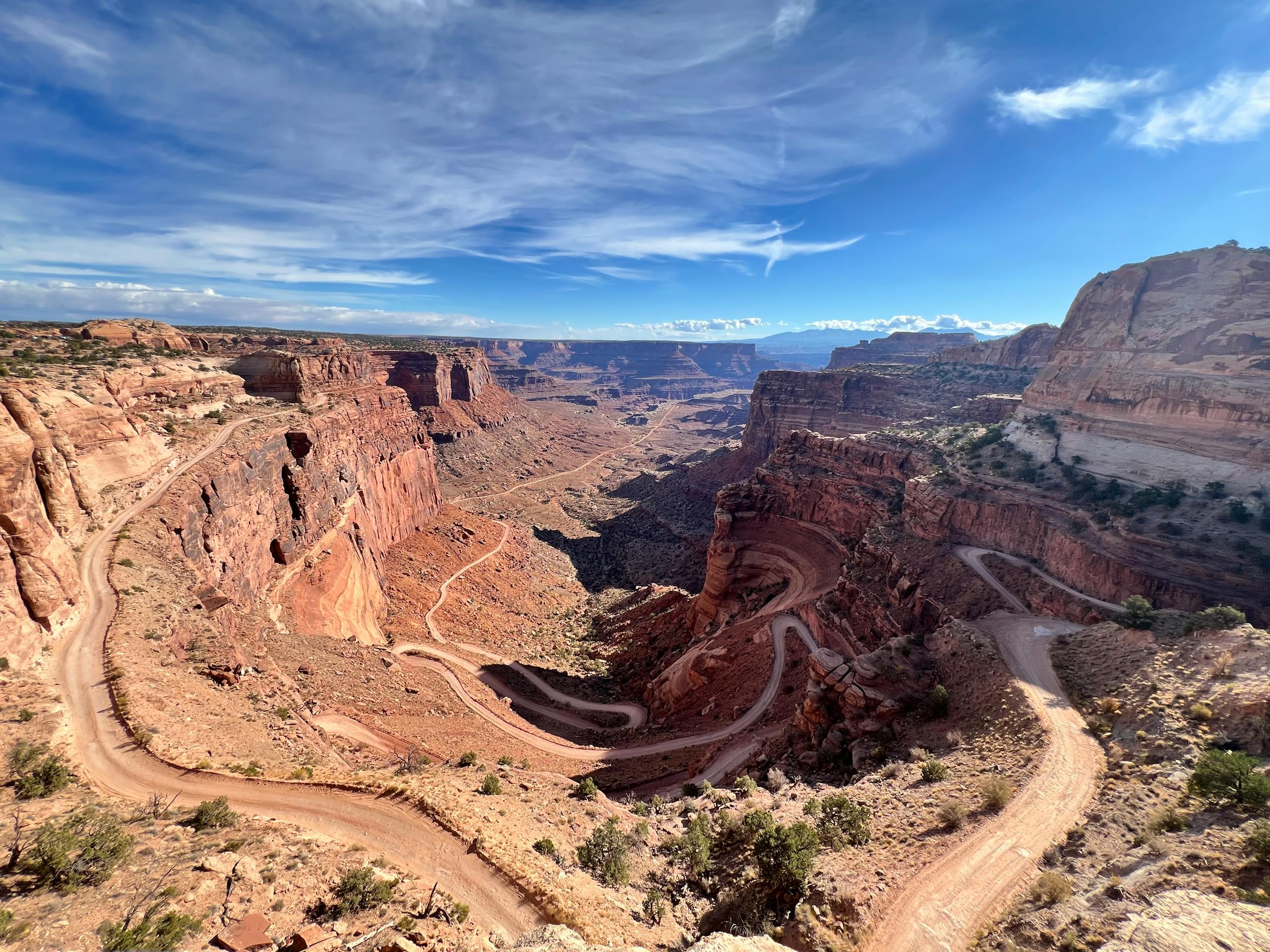 A breathtaking view of a red rock canyon with a winding dirt road under a clear blue sky.