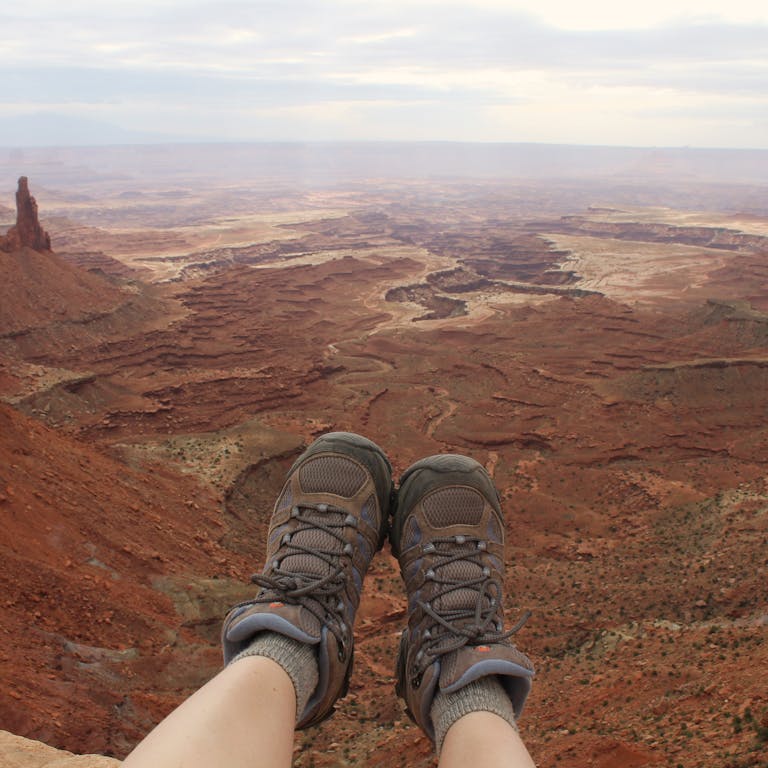 Hiker's boots overlooking the stunning landscape of Canyonlands National Park in Moab, Utah.