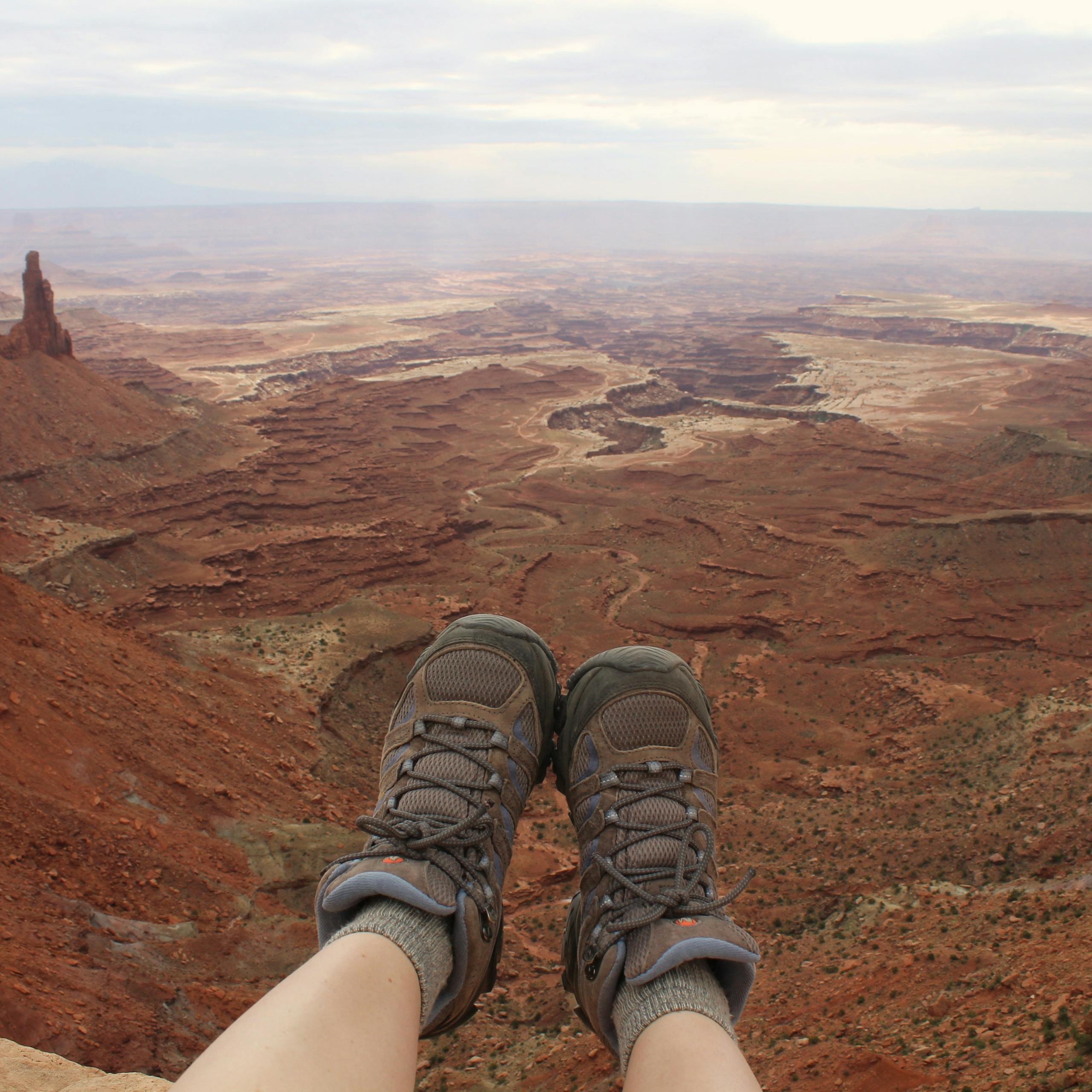 Hiker's boots overlooking the stunning landscape of Canyonlands National Park in Moab, Utah.