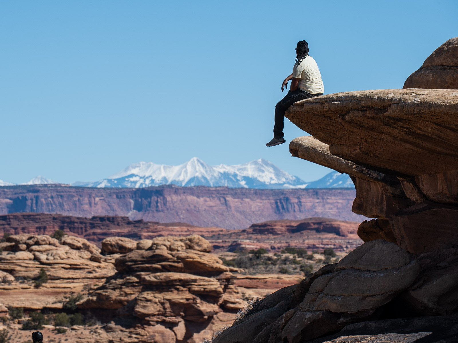 Sitting on top of a rock admiring the view of the La Sal Mountains from the needles district in Canyonlands National Park. wondering how many days do you need in Moab.