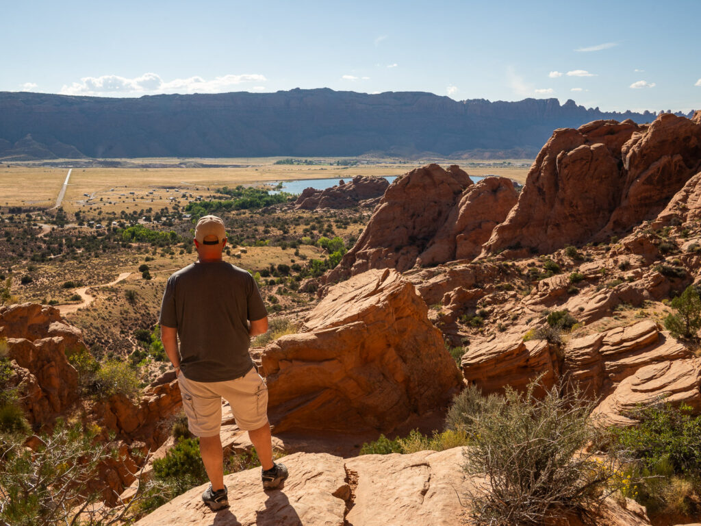 gabe at a viewpoint near Faux Falls looking towards Moab from a viewpoint surrounded by boulders