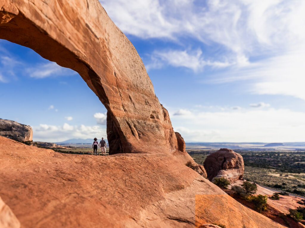 Rocio and Gabe standing under Wilson Arch taking in the panoramic view.