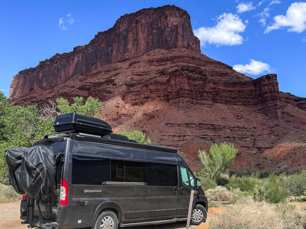 Camper van at a campsite in front of a red rock butte in Moab Utah