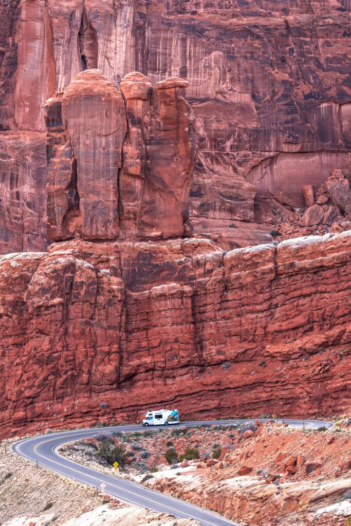 RV travels through stunning red rock formations in Moab, Utah, showcasing natural beauty and adventure.